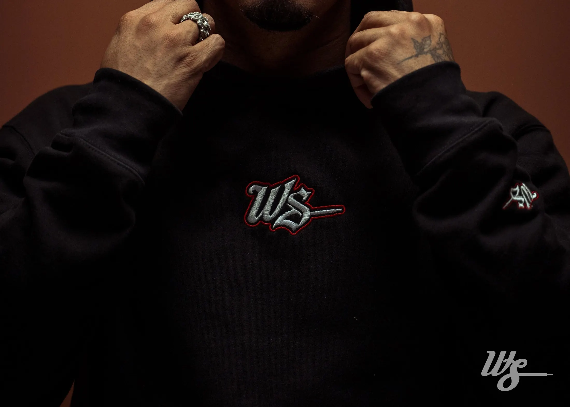 Detalle del hoodie WS Medieval con la firma bordada en rojo y blanco